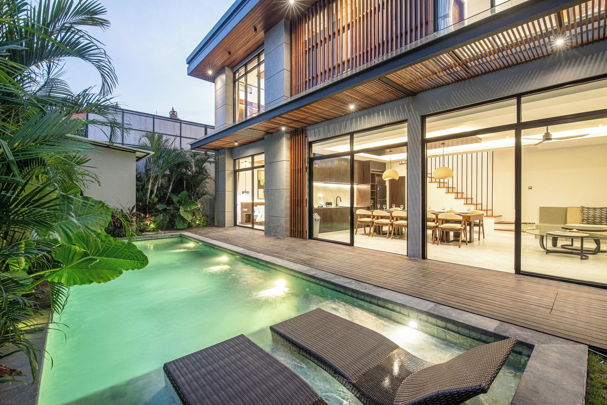 A modern house with a swimming pool, outdoor furniture, and a dining area.