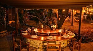 Ein Essbereich im Freien mit einem Steintisch, Holzstühlen und Kerzen.