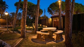A stone outdoor seating area with a circular table and benches, surrounded by trees and a brick building. - 15 min. drive from Sitges Villa El Ranch 10 min. walk to the beach Jacuzzi 12P (Sitges)