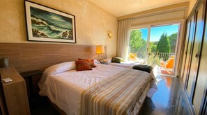 A hotel room with a bed, a nightstand, a lamp, a painting, and a balcony with chairs. - 15 min. drive from Sitges Villa El Ranch 10 min. walk to the beach Jacuzzi 12P (Sitges)
