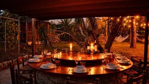 An outdoor dining area with a round table set for a meal, surrounded by chairs, with candles and string lights. - 15 min. drive from Sitges Villa El Ranch 10 min. walk to the beach Jacuzzi 13P (Sitges)