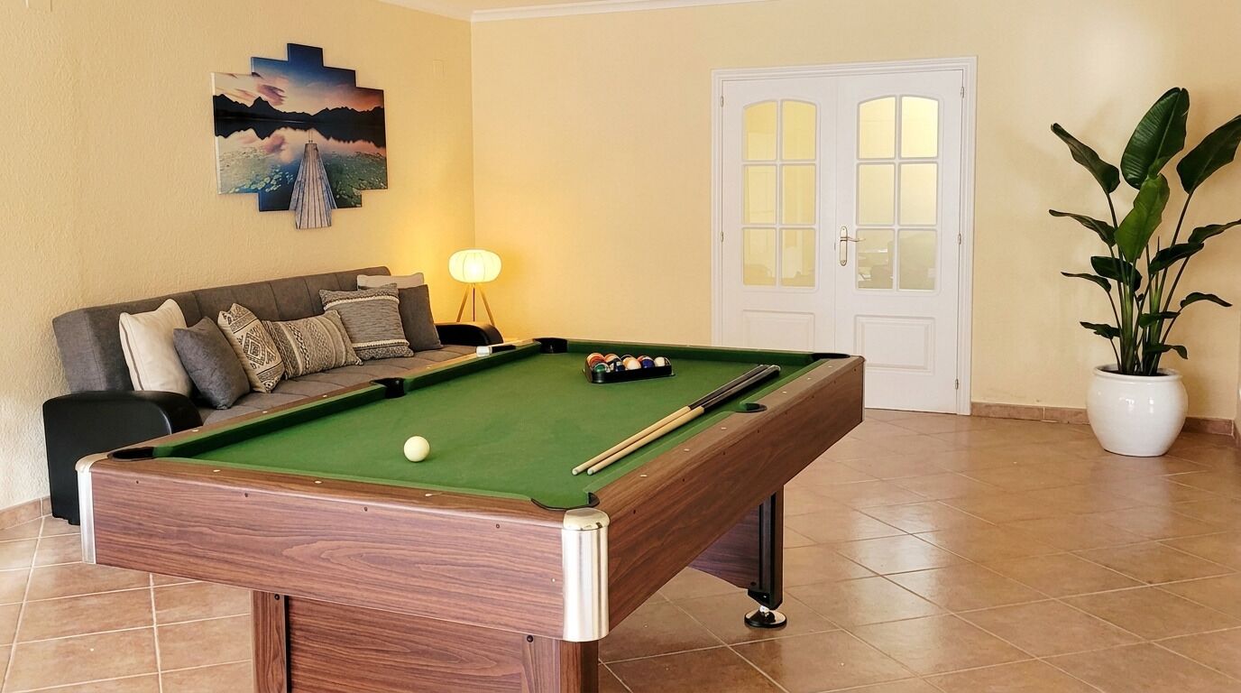 A pool table with balls, a sofa, a lamp, a door, and a potted plant.