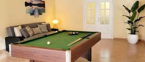 A pool table with balls, a sofa, a lamp, a door, and a potted plant.