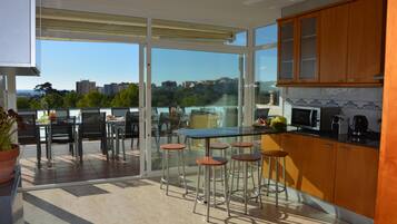 Een moderne keuken met uitzicht op de stad, een eethoek met barstoelen en een grote schuifdeur van glas.