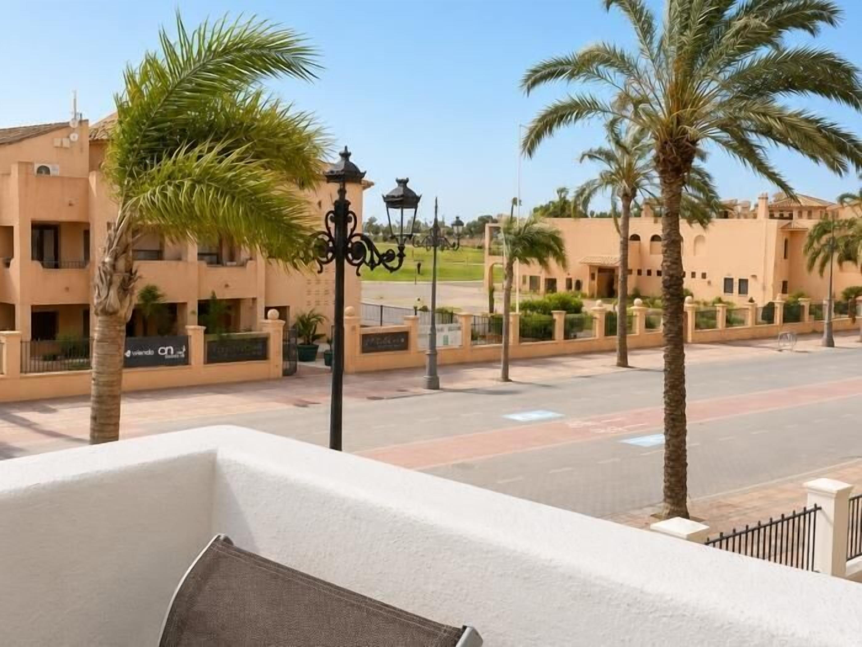 A residential area with palm trees, a street, and buildings with balconies.