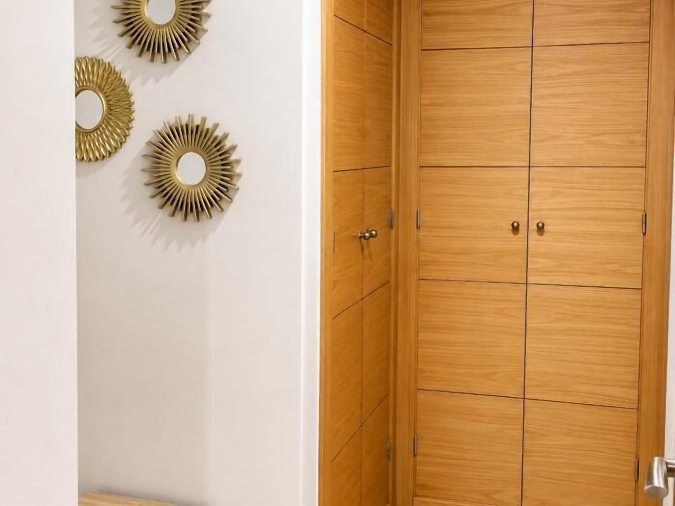 Un armario de madera con dos puertas y un espejo pequeño.