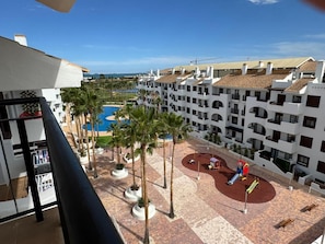Ein Hotelinnenhof mit Pool, Palmen und einem Spielplatz.