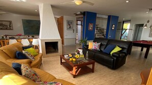 Ein Wohnzimmer mit Kamin, Billardtisch und einer Couch.