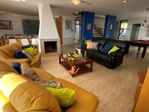 Ein Wohnzimmer mit Kamin, Billardtisch und einer Couch.