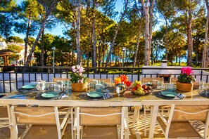 An outdoor dining area with tables set for breakfast, surrounded by trees and a view of the sea. - Villa Playa del Sur · 250m from the sea · 7 Suites · +19 guests · Views 10 P (Capafonts)