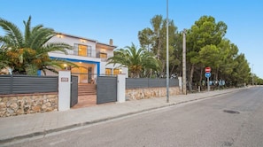 A modern two-story house with a stone wall and metal gates, a clear sky, and a no-entry road sign. - Villa Playa del Sur · 250m from the sea · 7 Suites · +19 guests · Views 10 P (Capafonts)