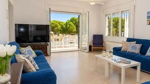 Een woonkamer met een televisie, twee banken, een salontafel en een balkon met buitenmeubilair.