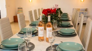 Ein Esstisch gedeckt mit türkis-farbenen Tellern, Weingläsern und Flaschen Clos Vidal Wein.