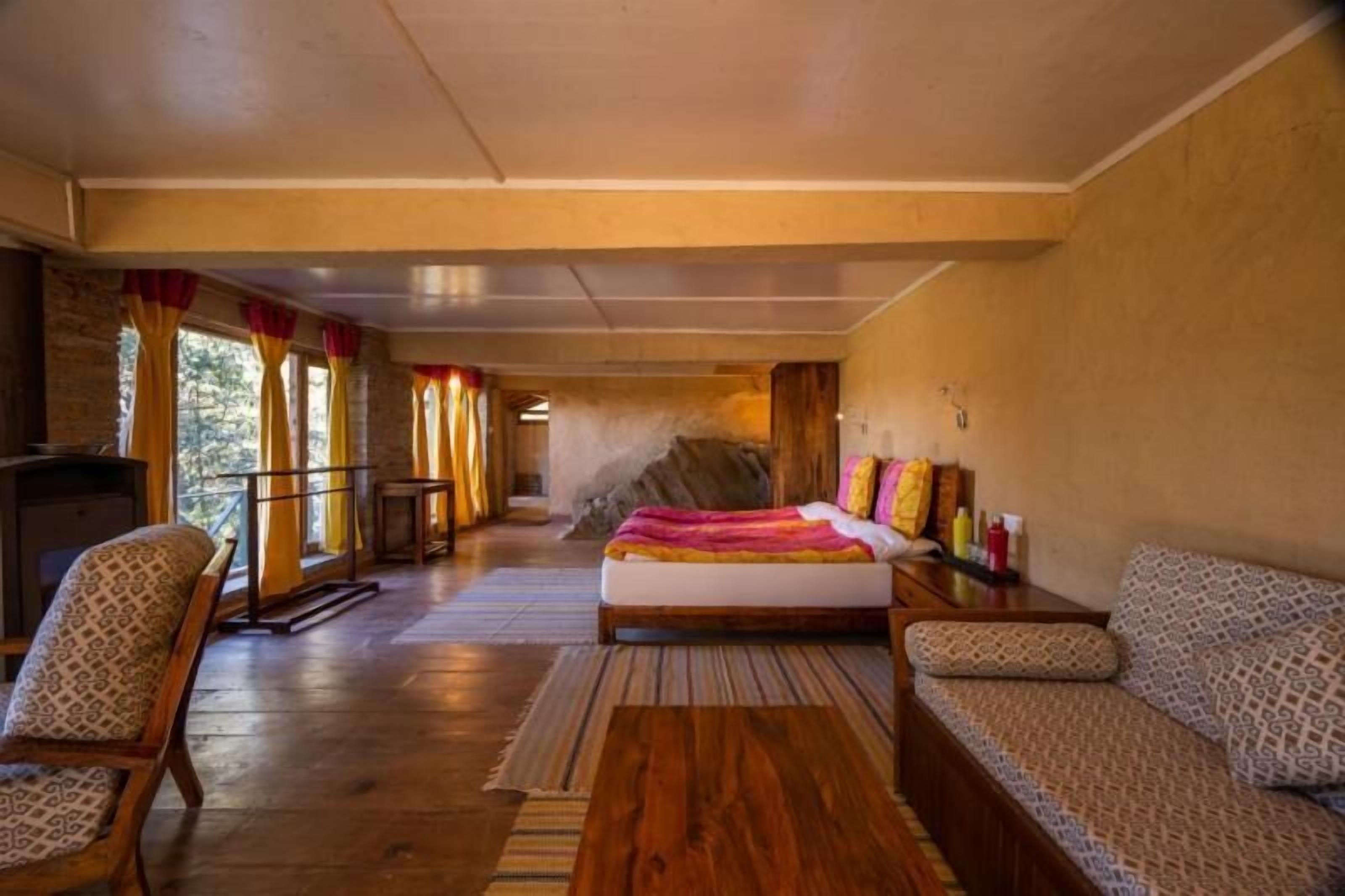 A spacious room with a large bed, a sofa, a chair, and a small table.