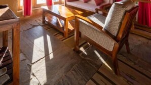 A room with a high ceiling, a wooden bench, a sofa, and a table. - Binsar Forest Retreat (Binsar)