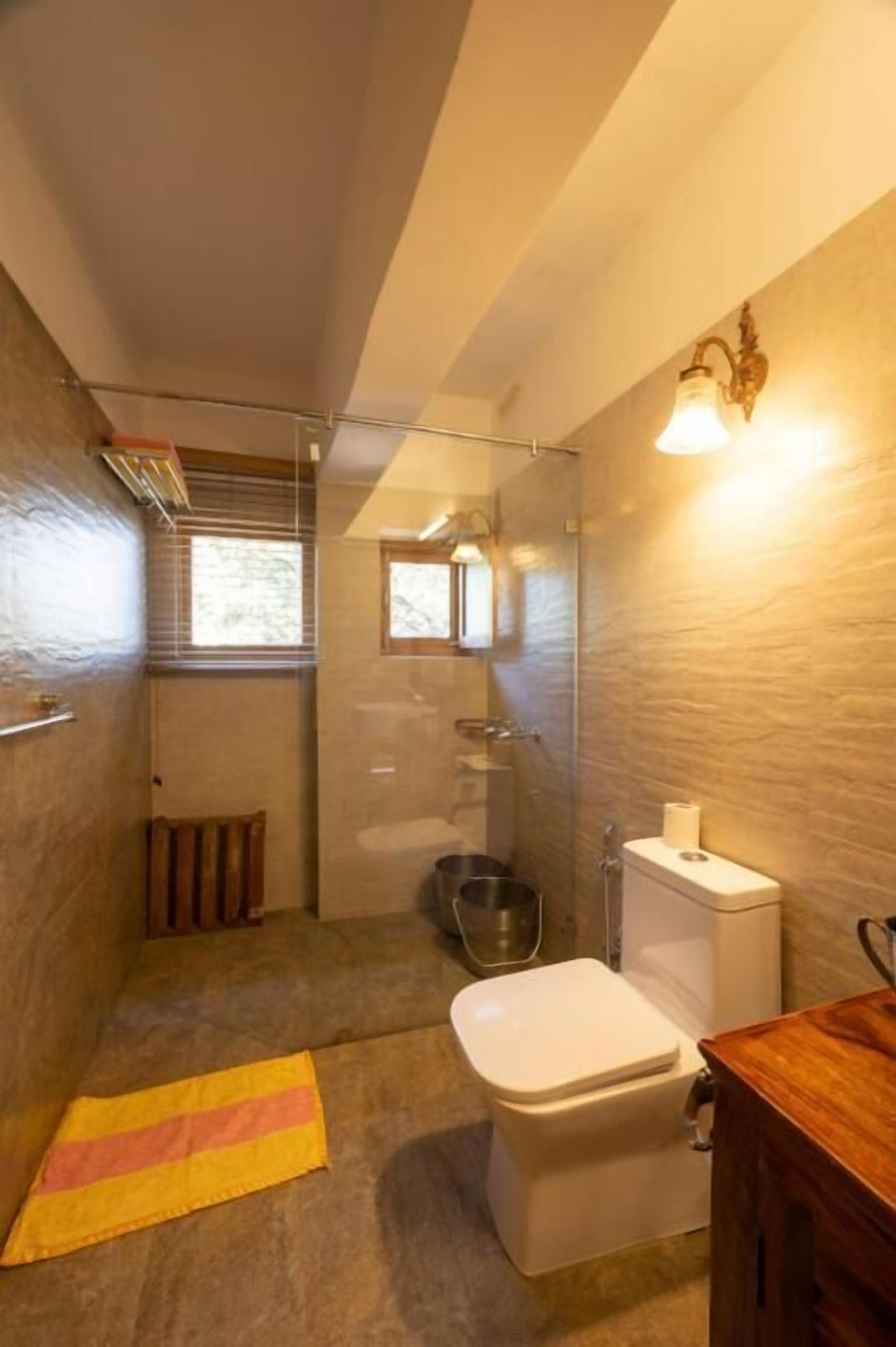 A compact bathroom with a toilet, a shower area, and a small window.