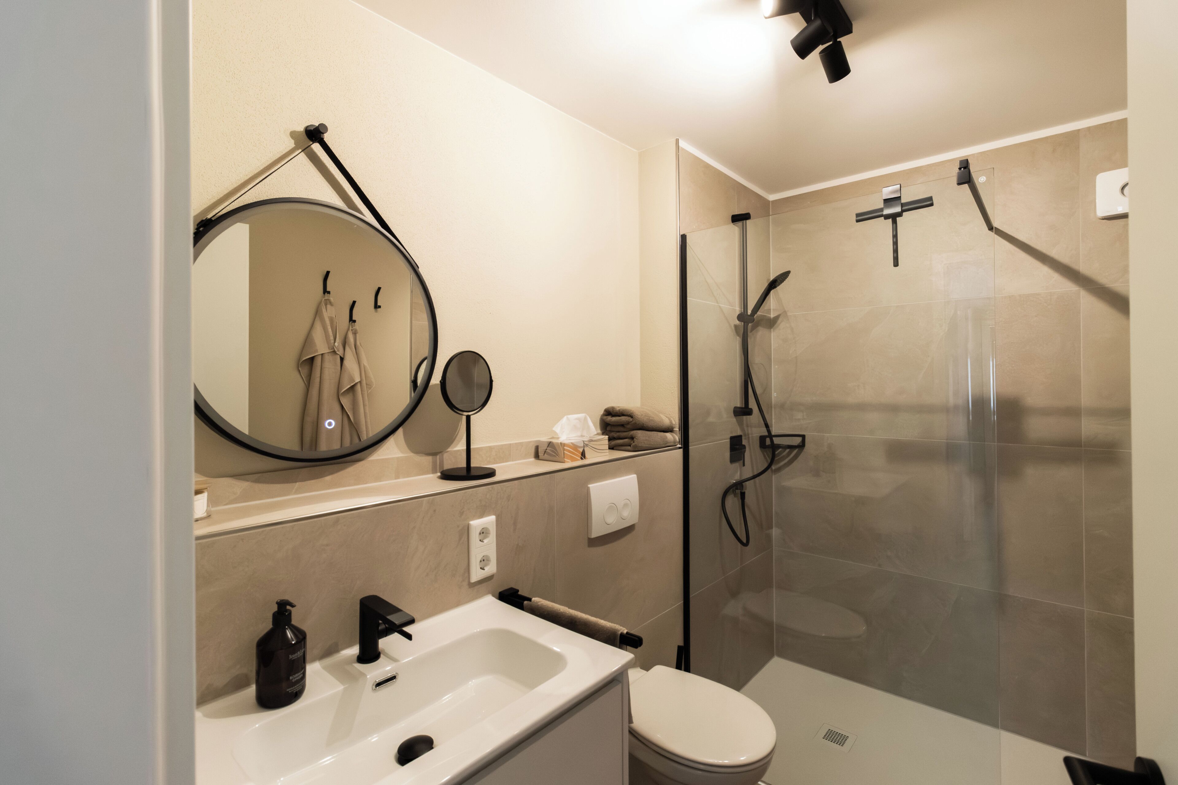 Ein modernes Badezimmer mit Waschbecken, Spiegel und Toilette.