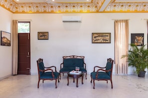 A room with a sofa set, two chairs, a small table with a glass and fruit, and a potted plant. - Alaya stays Haven Villa 3BHK with Pool (Bhankrota)