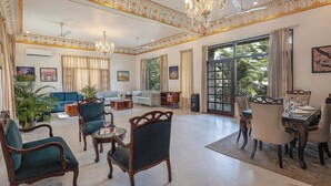 A spacious living room with a dining area, large windows, and elegant chandeliers. - Alaya stays Haven Villa 3BHK with Pool (Bhankrota)