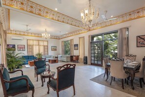 A spacious living room with a dining area, large windows, and elegant chandeliers. - Alaya stays Haven Villa 3BHK with Pool (Bhankrota)
