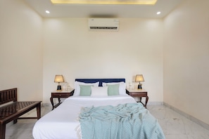 A hotel room with a bed, bedside lamps, a bench, and an air conditioning unit. - Alaya stays Haven Villa 3BHK with Pool (Bhankrota)