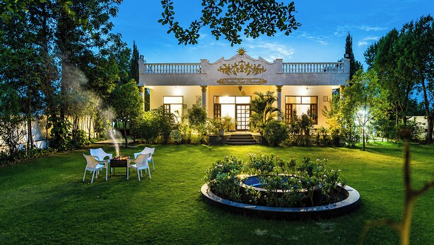 A hotel with a formal entrance, a well-maintained lawn, and a circular garden feature. - Alaya stays Haven Villa 3BHK with Pool (Bhankrota)