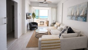 Ein modernes Wohnzimmer mit einer Couch, Sesseln, einem Couchtisch und einem Fernseher.