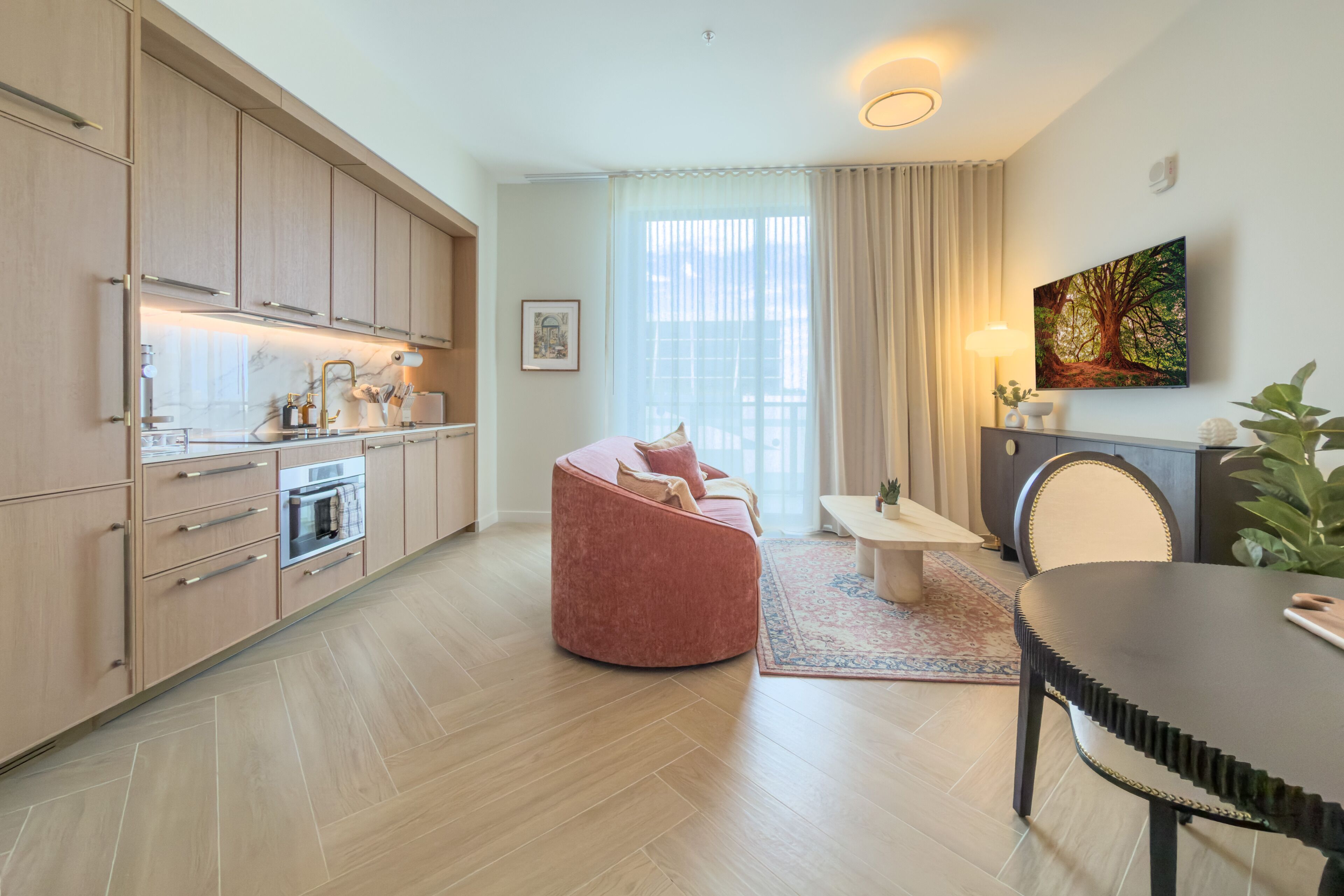 Een moderne keuken met inbouwapparatuur, een eethoek met tafel en stoelen, en een woonruimte met een bank.