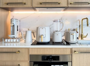 Eine moderne Küche mit Kaffeemaschine, Heißluftfritteuse, Mixer und Toaster auf der Arbeitsfläche.