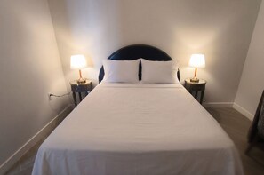 Ein Hotelzimmer mit einem Einzelbett, zwei Nachttischlampen und einer Steckdose an der Wand.