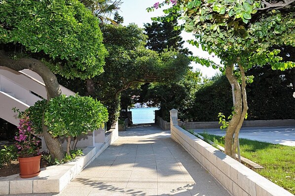 A pathway leading to a pool with surrounding greenery and a potted plant. - Amazing Place 4 Peaceful Holiday L (Poljana)