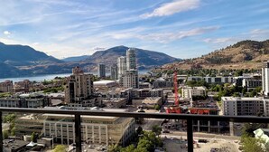 Une vue urbaine avec des immeubles, une grue de construction et des montagnes en arrière-plan.