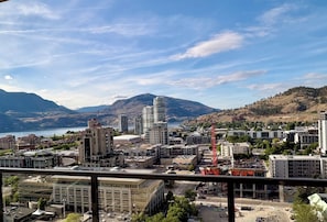 Un paisaje urbano con edificios, una grúa de construcción y montañas al fondo.