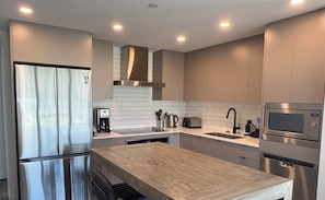 Una cocina moderna con electrodomésticos de acero inoxidable, una isla de madera y azulejos blancos tipo metro.