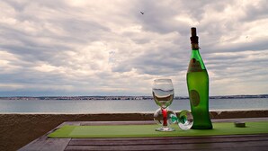A table with a bottle and a glass, overlooking a body of water and a distant cityscape. - Amazing Place 4 Peaceful Holiday apartman PIA (Poljana)