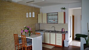 A compact kitchen with a dining area, a brick wall, and modern cabinetry. - Amazing Place 4 Peaceful Holiday apartman PIA (Poljana)