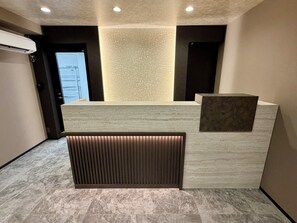 A reception area with a marble reception desk, a textured wall, and a recessed lighting panel. - KITAYAMA HOTEL ASAKUSA (Taito-ku)