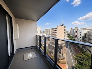 Un balcón con vistas a la ciudad, una reja en el suelo y un dispositivo blanco montado en la pared.
