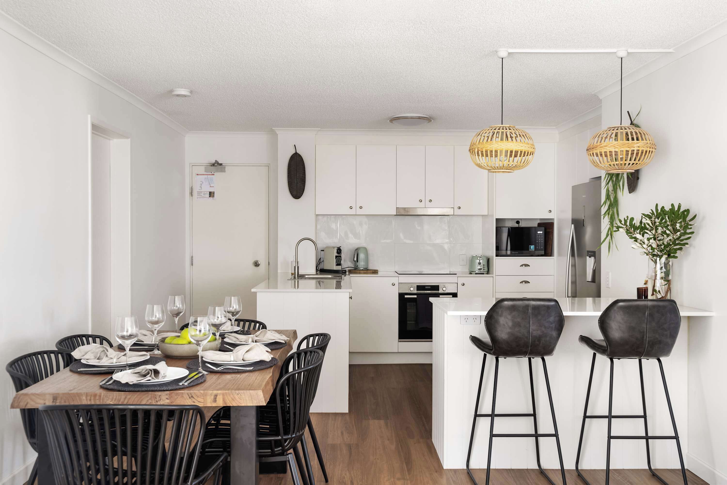 A modern kitchen with white cabinets, a central island, and black bar stools.