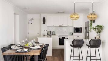A modern kitchen with white cabinets, a central island, and black bar stools.