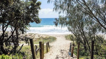 A sandy beach path with wooden posts, leading to the ocean.