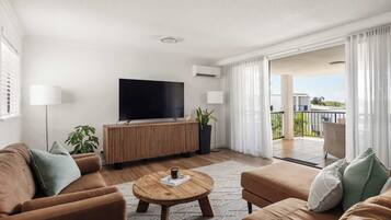 A modern living room with a flat-screen TV, wooden coffee table, and sofas.