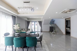 Ein zeitgemäßer Essbereich mit einer Deckenleuchte, einer Treppe und Blick ins Freie.