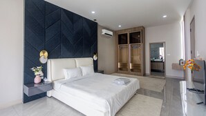 Ein modernes Schlafzimmer mit einem großen Bett, einer dunklen Akzentwand, einem Kleiderschrank und einem durch eine offene Tür einsehbaren Badezimmer.