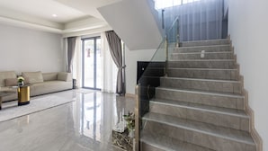 Ein modernes Wohnzimmer mit einer Couch, einem Couchtisch und einer Treppe mit Glastrennwand.