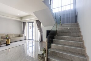 Ein modernes Wohnzimmer mit einer Couch, einem Couchtisch und einer Treppe mit Glastrennwand.