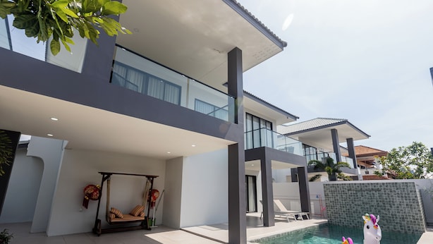 Ein modernes Haus mit Schwimmbad, einer Schaukelstuhlsitzgelegenheit und einem dekorativen Schwanein Schwimmer.