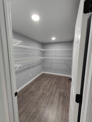A room with a grey wall, wooden flooring, and white shelving units.