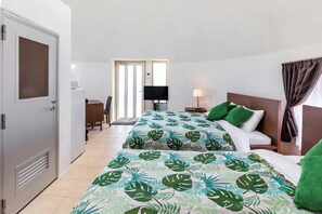 Quarto de hotel com cama, escrivaninha, televisão e janela com cortinas.