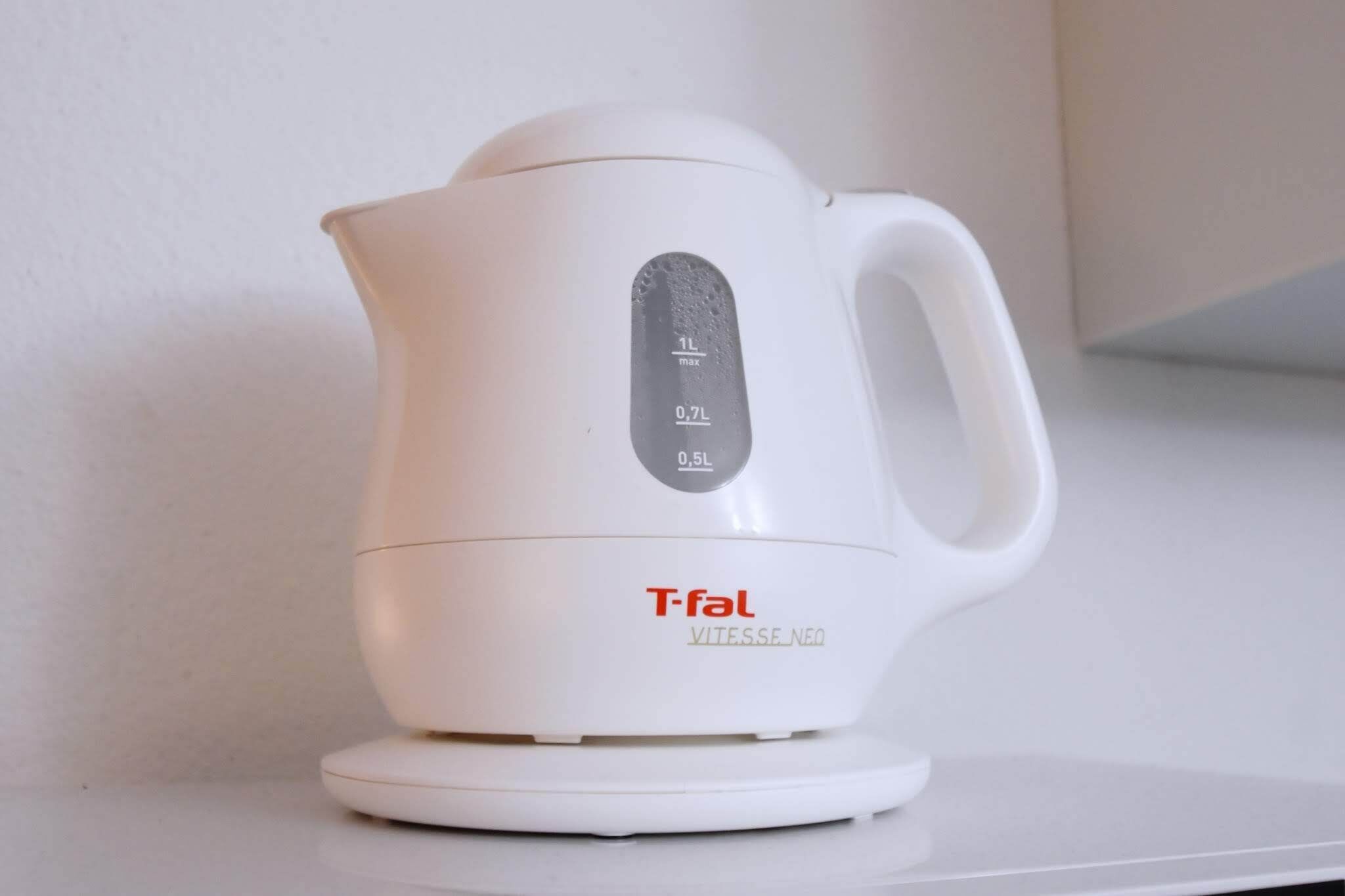 A white electric kettle with measurement markings and the brand name "T-fal" on a white surface.